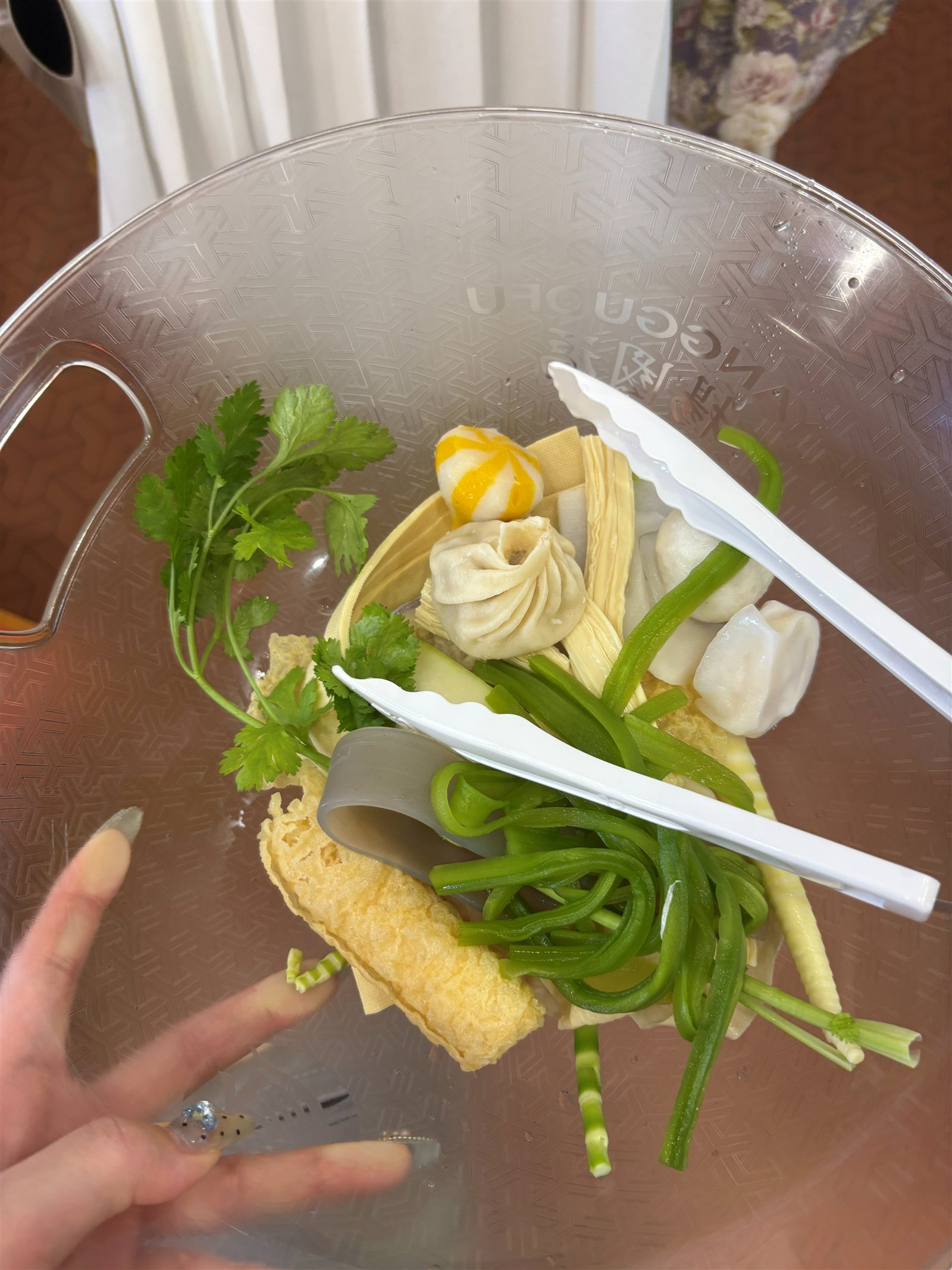 麻辣湯の量り売りで選んだ具材、湯葉や小籠包、パクチーなどをトングで持ち上げたところ