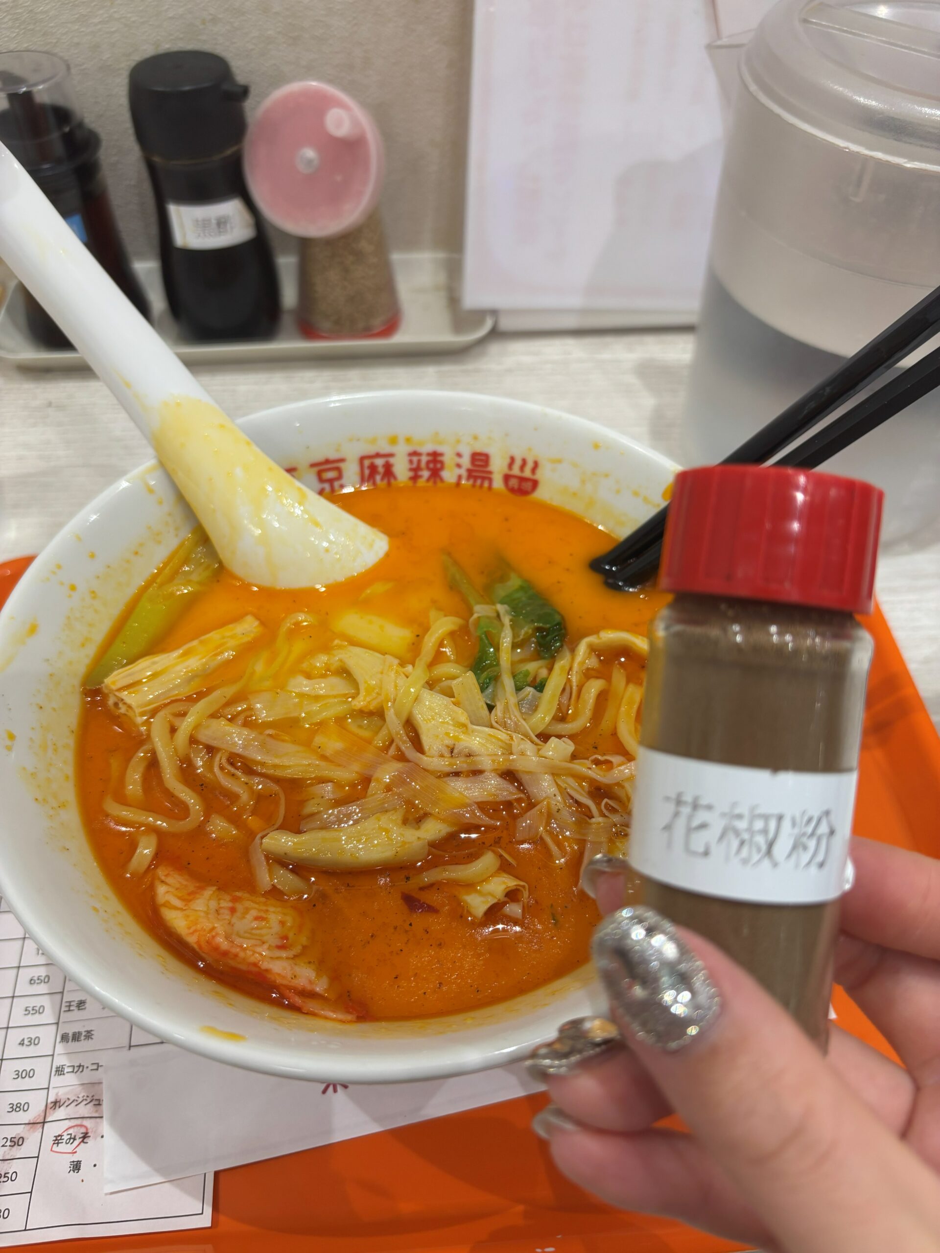 東京麻辣湯 ペリエ千葉店の麻辣湯に花椒粉を追加する様子