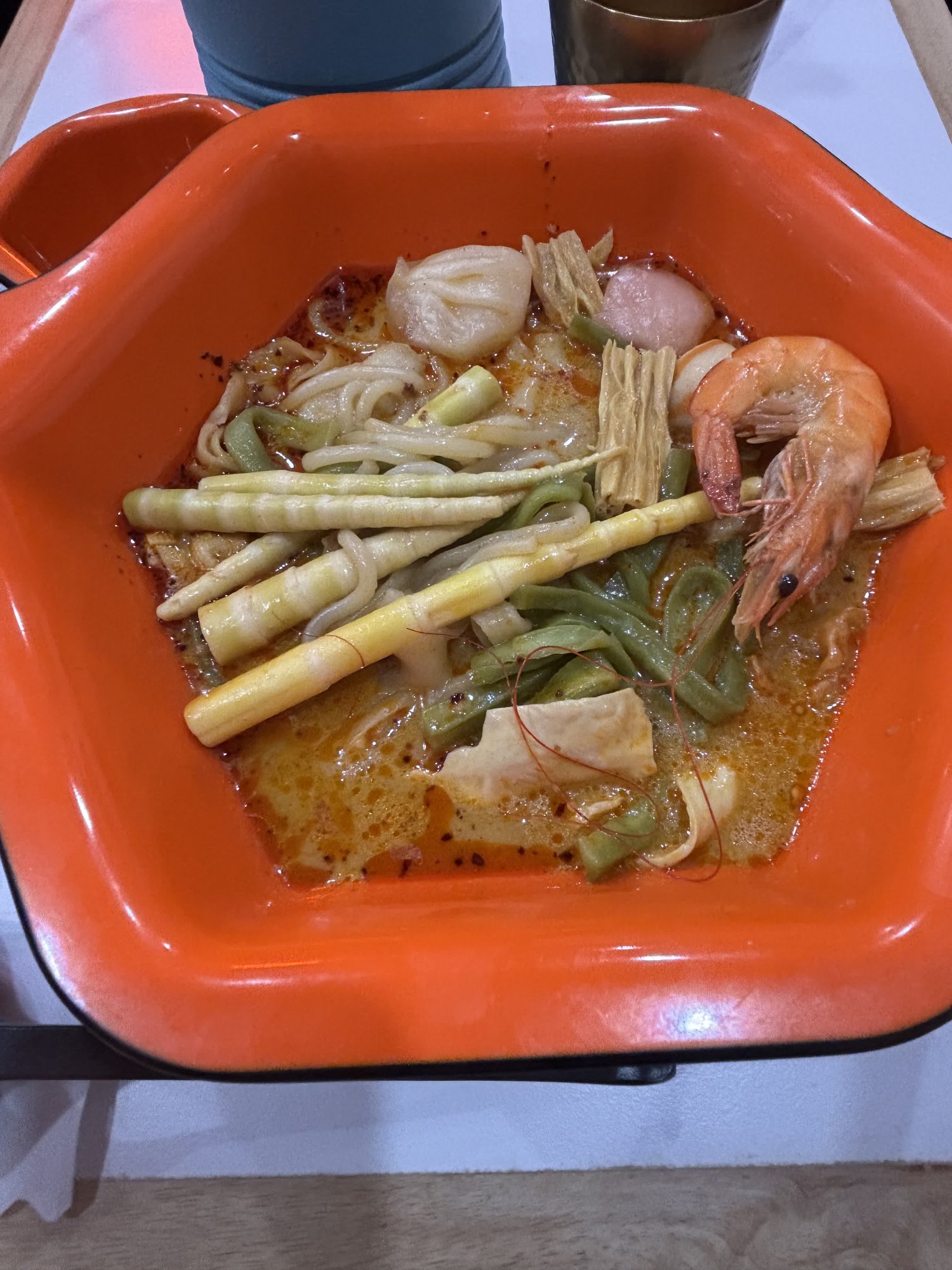 オレンジ色の器に入った麻辣湯。エビがのっていて、ほかにも具材と麺が入っている