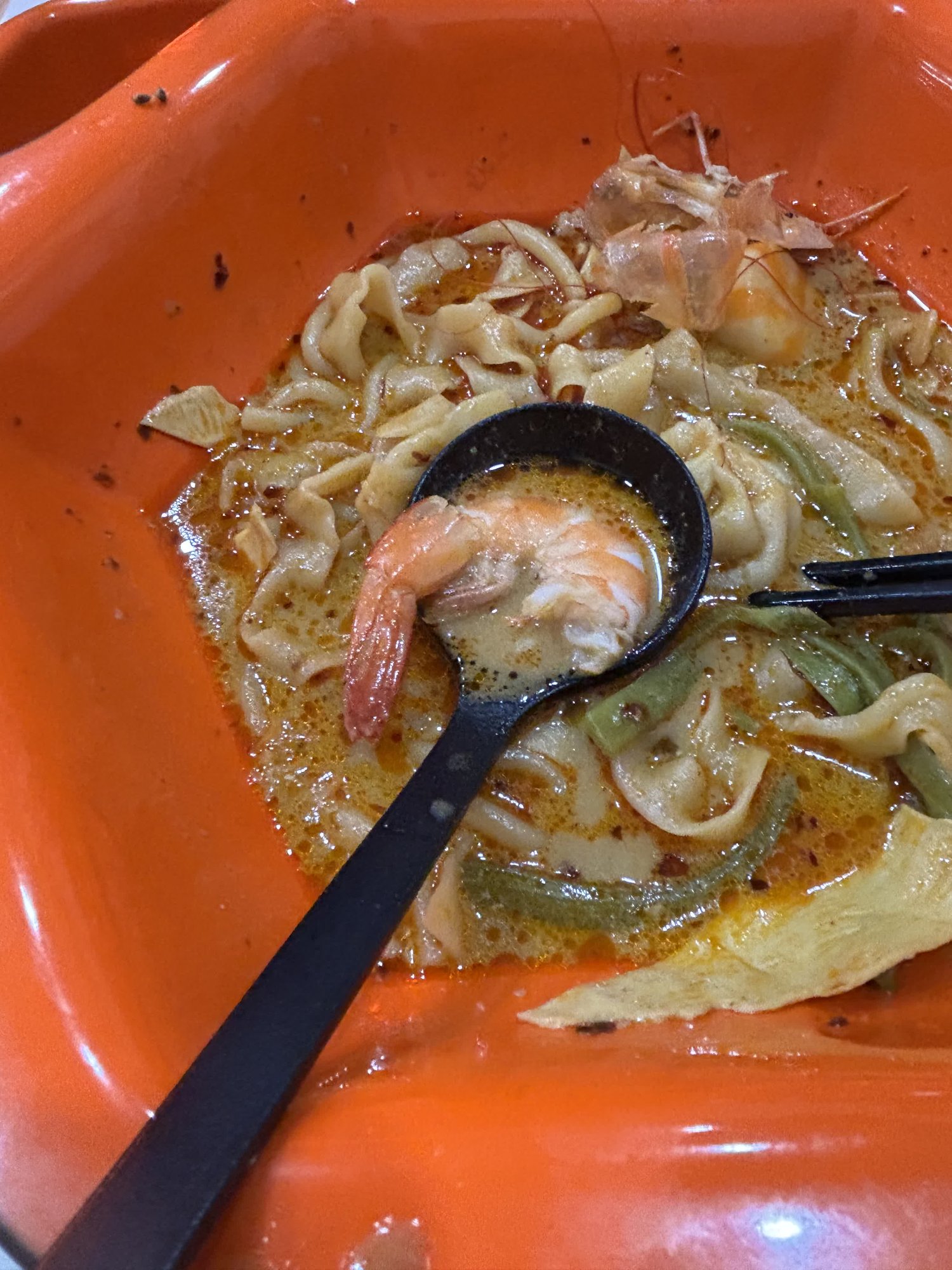 食べ進めた途中の麻辣湯。レンゲの上にエビがのっていて、器には麺とスープが残っている